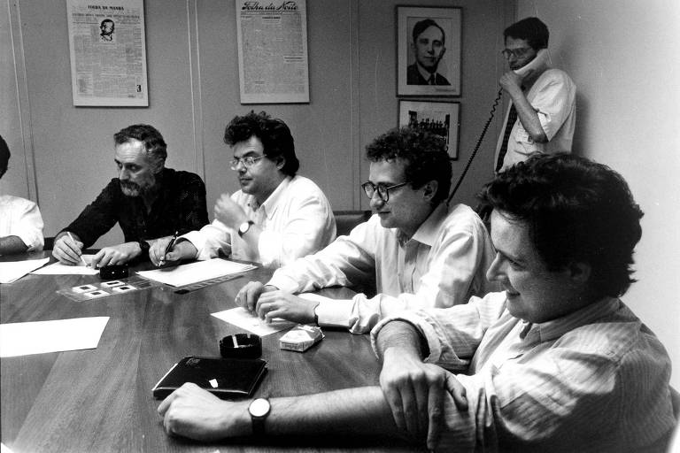 Reunião em sala na sede do jornal em 1989, com o diretor de Redação, Otavio Frias Filho, ao telefone ao fundo. À mesa, a partir da esq., Clovis Rossi, Bernardo Ajzenberg, Artur Ribeiro Neto e Marcelo Coelho