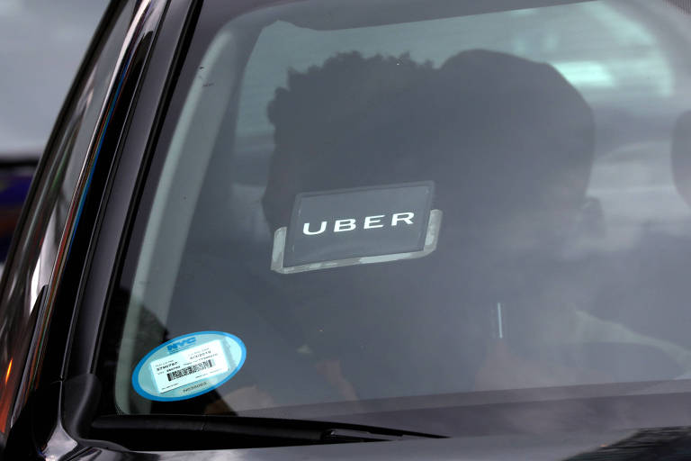An Uber logo is seen on a car as it car drives 