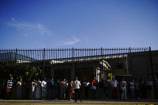 People listen to a U.S. Embassy employee prior to entering the complex in Havana