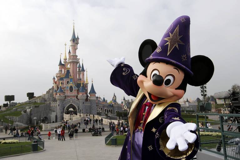 Mickey com chapéu de bruxo em frente a castelo
