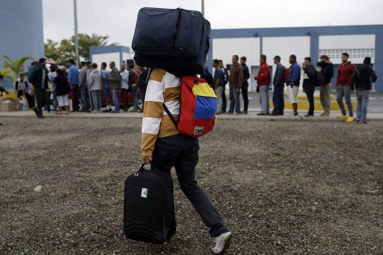 Migrante venezuelano caminha até o Peru enquanto outros aguardam pelo café da manhã na cidade de Tumbes