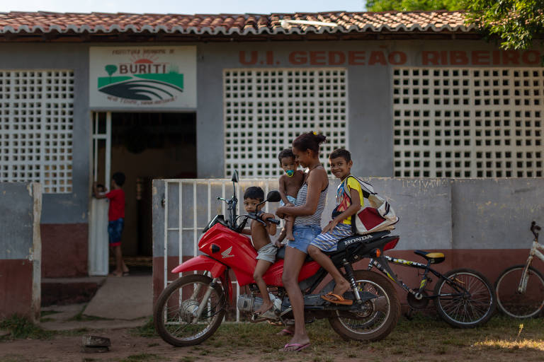 Patricia Maria da Silva Souza, 25, com o irmão Fabio Souza, 9 (na garupa), e os filhos Felipe da Silva Souza, 1 (chupeta) e Davi Luiz, 3, em frente a escola rural Gedeão Ribeiro, em Buriti (MA).