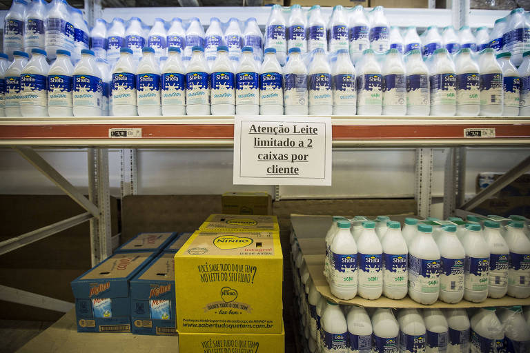 Estante de supermercado com embalagens de leite longa vida e placa que diz "Atenção: Leite limitado a 2 caixas por cliente"