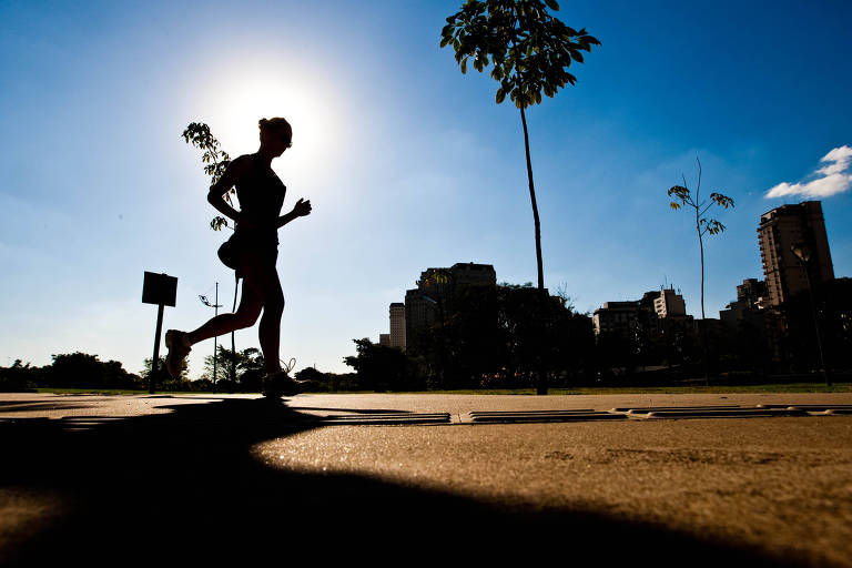 Mulher corre, no Parque do Povo, em dia seco e quente, em São Paulo (SP)