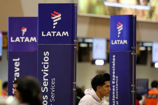 Passengers walk near the LATAM airlines counter at Jorge Chavez airport in Callao