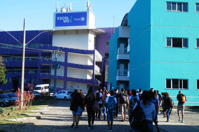 Alunos entrando na escola, um grande prédio azul