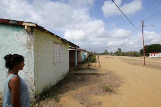 A woman walks next to houses near Atapirire