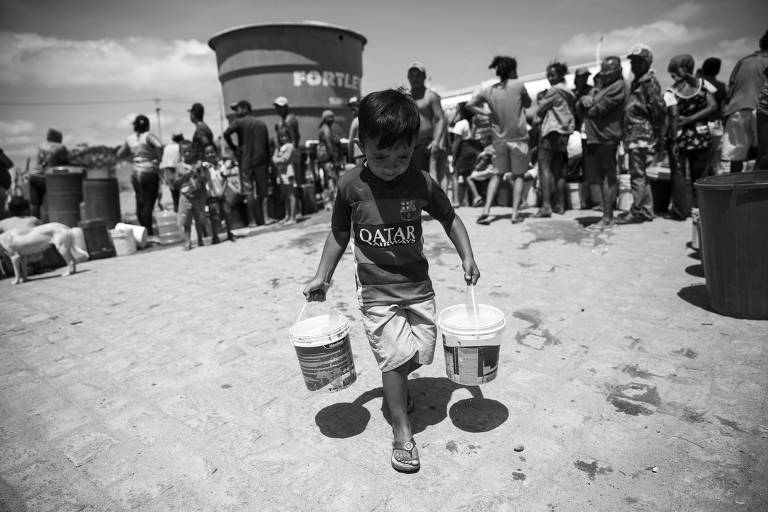 Luiz Fernando, 4, carrega baldes de água que serão usados durante a semana, em Poção (PE)


