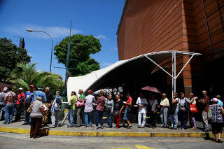 People line up to withdraw a part of their pensions outside a bank branch in Caracas