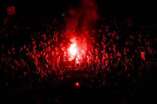 People with flares react during an open air 