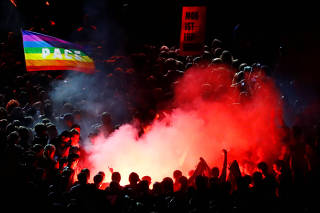 Anti-fascist activists with flares react during an open air 