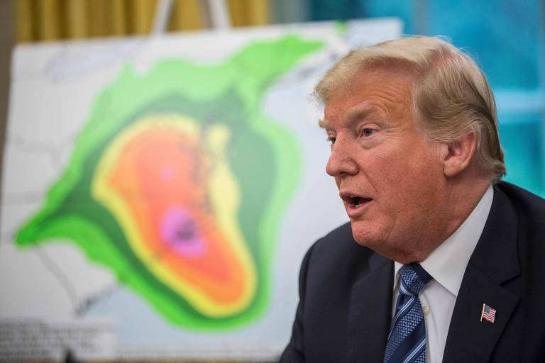 Trump aparece de perfil. À sua esquerda, um mapa do avanço do furacão.