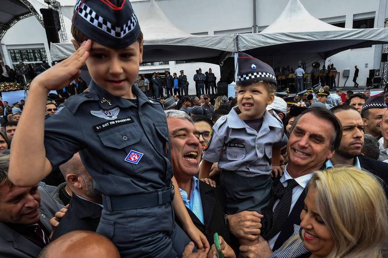 Os candidatos  do PSL à Presidência Jair Bolsonaro e Senado Major Olímpio, seguram crianças vestidas com uniforme da PM durante a cerimônia de formatura de uma escola militar em São Paulo