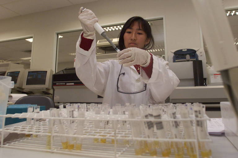 Mulher manipula tubos de ensaio em laboratório
