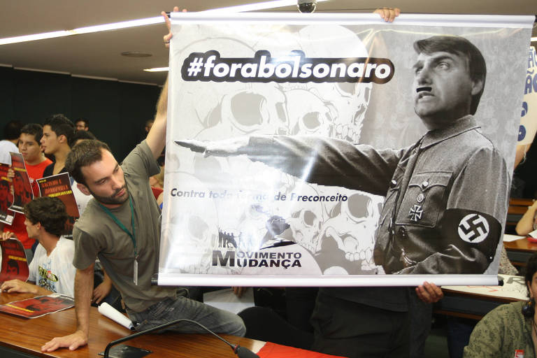 Manifestantes ligados à União Nacional dos Estudantes (UNE) e a movimentos de esquerda fazem protesto na Comissão de Direitos Humanos da Câmara dos Deputados comparando o deputado Jair Bolsonaro (PP-RJ) a Adolf Hitler; à época, ele começou a se envolver mais em polêmicas sobre opiniões consideradas racistas e homofóbicas e por brigar com a colega Maria do Rosário
