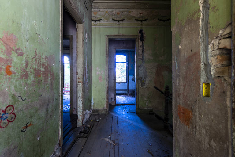 Corredor do piso superior, onde ficavam os quartos, deixa ver restos de ocupação irregular dos anos 2000; no alto, notam-se pinturas em estilo art-nouveau que sobreviveram