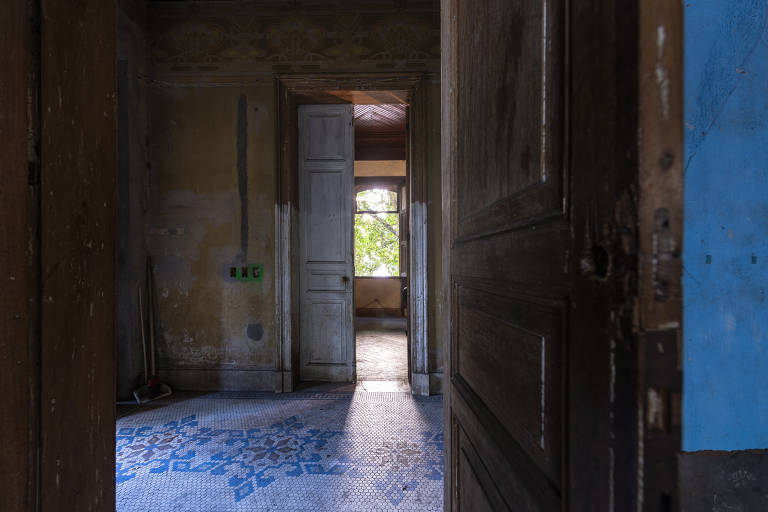 Entrada da casa, vista a partir da sala de estar, que fica à direita de quem entra; note-se o mosaico do piso original