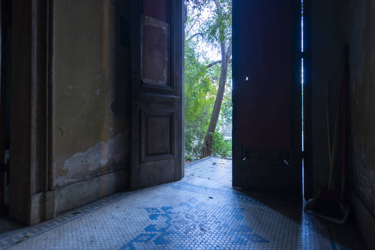 Entrada da casa, com suas portas de madeira, vista a partir do saguão com piso de mosaico
