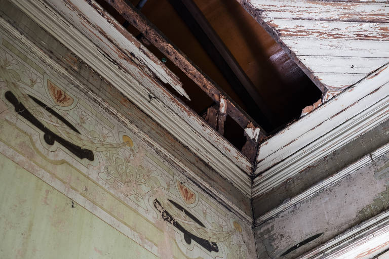 Detalhe de pinturas art-nouveau no alto da parede do piso superior; vê-se também o forro destruído
