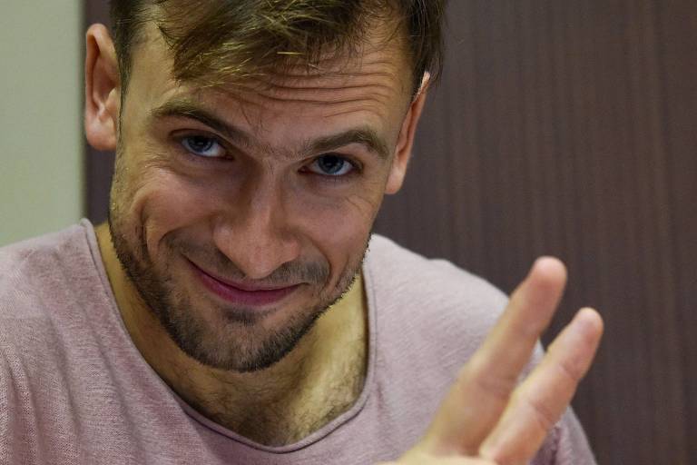 Piotr Verzilov sorri e faz sinal da paz com os dedos