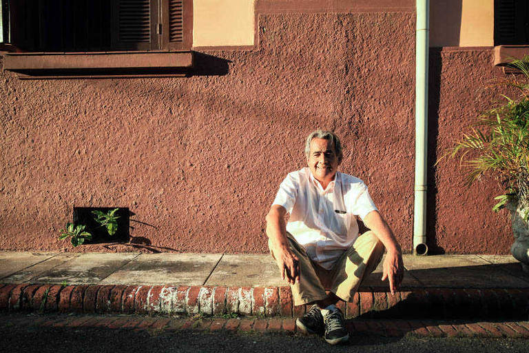 Morador da Vila Maria Zélia está sentado na calçada em frente a sua casa