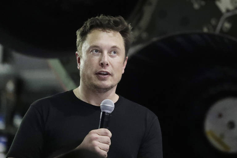 Elon Musk de camiseta preta e microfone na mão