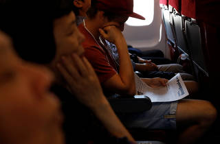 A foreign tourist reads Pypngyan Times, a weekly newspaper as others rest on an Air Koryo flight to Pyongyang