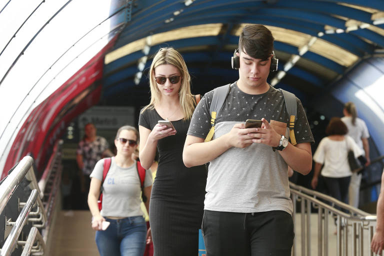 Passageiros caminham pela estação Barra Funda do Metrô manuseando aparelhos de celular