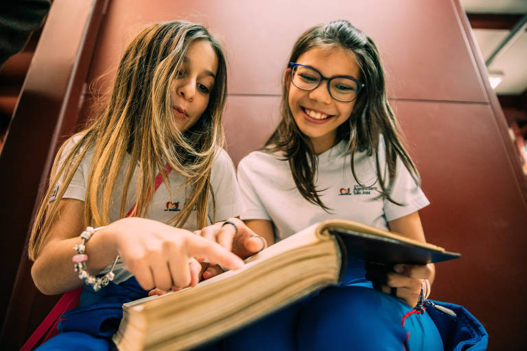 Luiza Alarcon, 10, à esquerda, e Ana Theresa Jimenes, 10, consultam um livro; o desafio da Folha é que elas não acessem o celular

