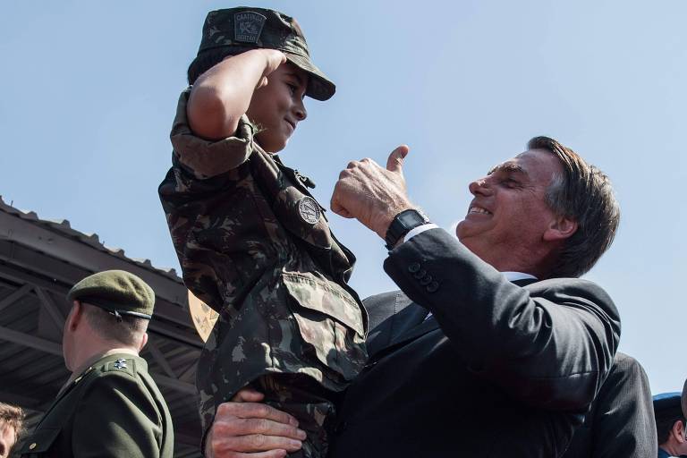 O deputado e presidenciável Jair Bolsonaro (PSL) segura e cumprimenta um garoto com uniforme militar durante evento em São Paulo
