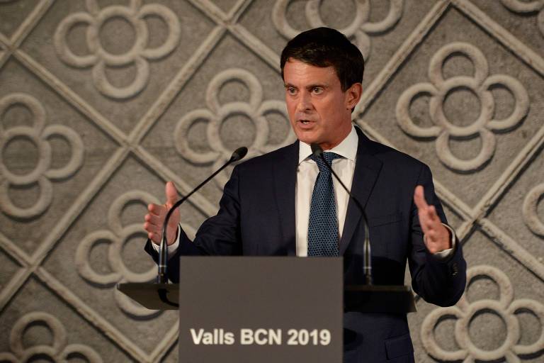 Valls faz gesto de abrir as mãos enquanto fala em um púlpito preto, com a frase "Valls BCN 2019"
