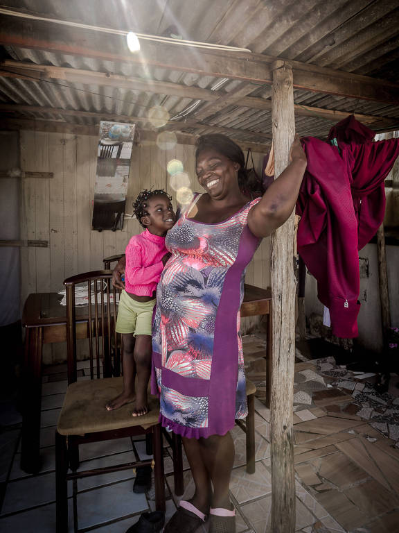 A haitiana Elisa Derisma Maesclin, 43, em sua casa no terreno invadido batizado de Ocupação Progresso, em Porto Alegre. Desde 2014, ela e centenas de haitianos ergueram barracos no local. Antes, viveu 13 anos na Venezuela. A filha de 16 anos foi viver com o pai nos Estados Unidos. A do meio, de 14, ficou na Venezuela com parentes. O novo marido de Elisa aceitou uma oferta de trabalho na ilha de Martinica, e ela partiu para tentar a sorte no Brasil, sozinha e grávida da terceira filha