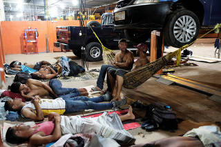 Venezuelan people are pictured on their improvised beds during the night at the car repair shop, near the interstate Bus Station in Boa Vista