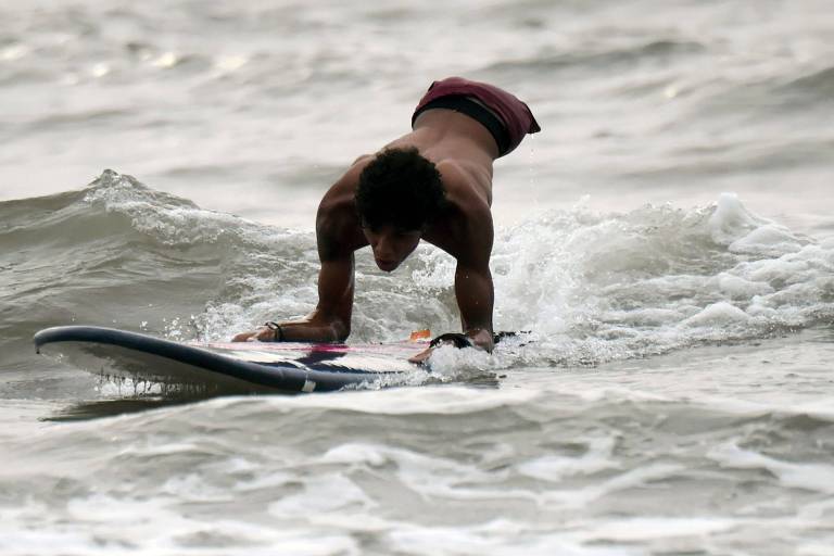 O venezuelano Alfonso Mendoza, o Alca, que não tem as penas, pratica surfe na praia de Puerto Colombia, próxima a Barranquilla, para onde migrou há nove meses, fugindo da crise econômica em seu país

