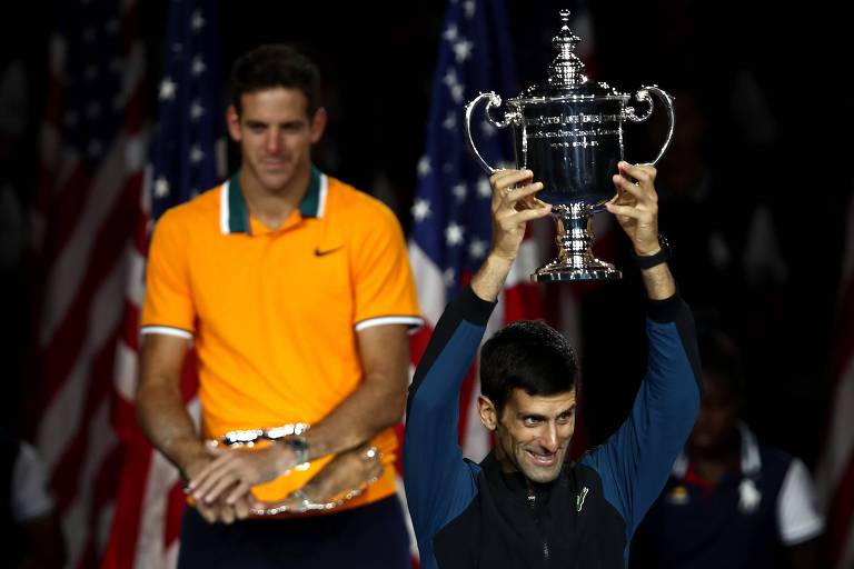 À frente, Novak Djokovic levanta o troféu do US Open. Ao fundo, o vice-campeão Juan Martin del Potro 