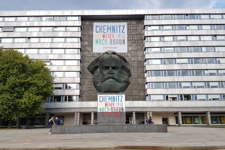Monumento Karl Marx, na Brückenstrasse, no centro de Chemnitz (Alemanha), em torno do qual acontecem protestos de simpatizantes da extrema direita; os cartazes coloridos trazem os dizeres "Chemnitz não é cinza nem marrom", nome de uma campanha lançada pela associação local das indústrias para tentar descolar da cidade a pecha de capital da intolerância