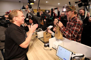 Canopy Growth CEO Bruce Linton applauds after handing Ian Power and Nikki Rose, who were first in line to purchase the first legal recreational marijuana after midnight, their purchases at a Tweed retail store in St John's