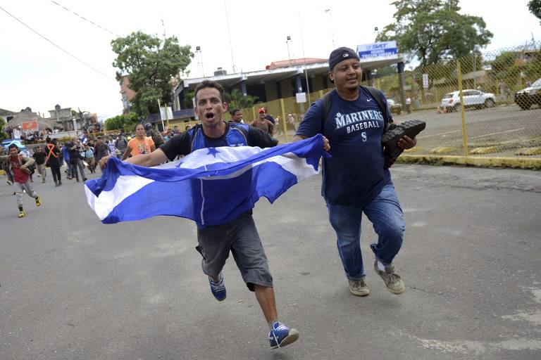 Hondurenhos correm na ponte da fronteira entre o México e a Guatemala, logo após terem rompido os portões que fechavam o acesso do lado guatemalteco