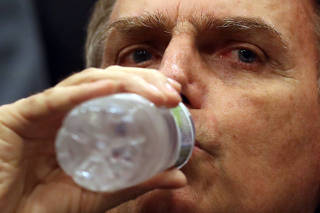 Presidential candidate Jair Bolsonaro drinks water as he attends a news conference in Rio de Janeiro