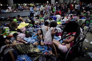 Migrants, part of a caravan of thousands of migrants from Central America en route to the United States, rest along the sidewalks of Tapachula