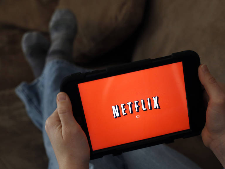 Pessoa segura um tablet em cuja tela aparece a logomarca da Netflix