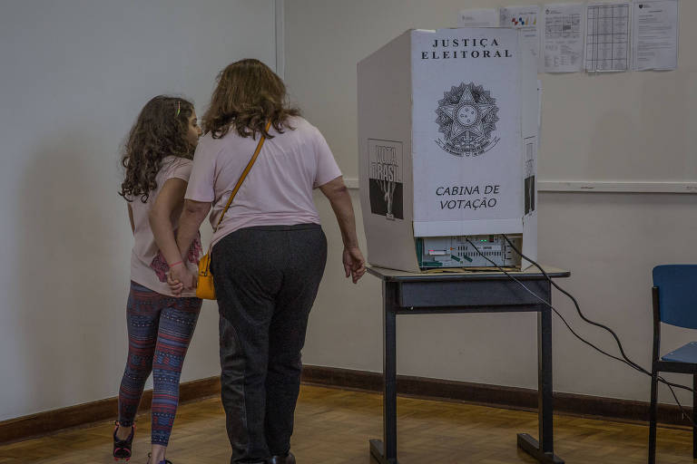 Eleitora acompanhada de criança vota no colégio Santo Américo, zona sul de São Paulo, no primeiro turno das eleições deste ano