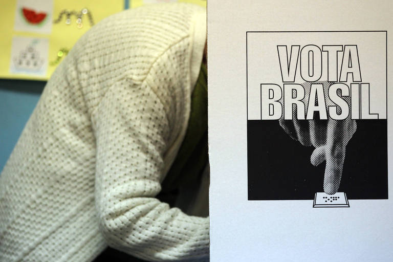 Pessoa atrás de urna com os escritos "vota brasil"