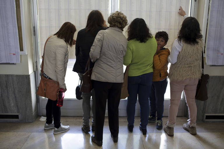 Eleitores procuram seus nomes na lista, em zona eleitoral de Lisboa, em Portugal