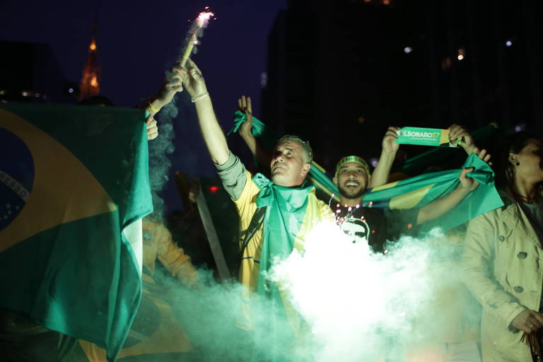 Homens seguram sinalizadores e bandeiras do Brasil