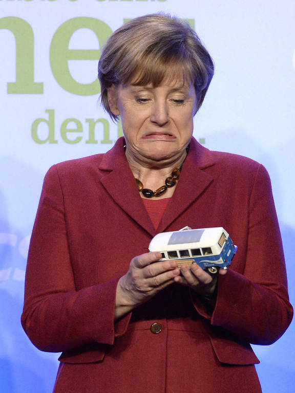 Angela Merkel faz careta com modelo de kombi da Volkswagen, durante campanha em Munique, na Alemanha