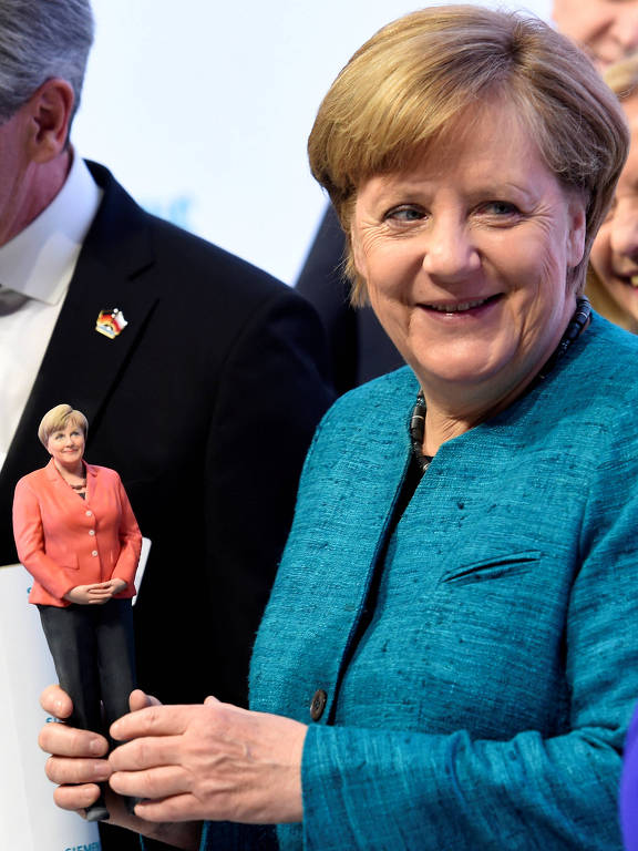 Angela Merkel segura boneca em 3D dela mesma em feira em Hannover, na Alemanha
