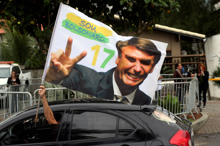 Eleitor de Jair Bolsonaro segura bandeira do presidente eleito no Rio de Janeiro