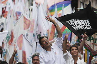 Fernando Haddad, presidential candidate of Brazil's leftist Workers Party (PT), and his wife Ana Estela flash the victory sign during a march for peace at Heliopolis slum in Sao Paulo