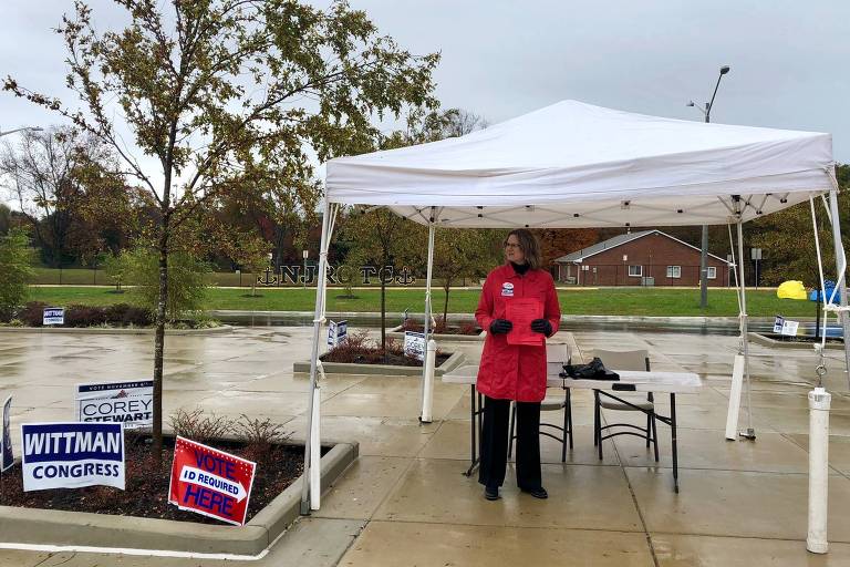 A eleitora republicana Gail Tabor, 61, distribui cédulas com nomes de candidatos em frente a posto de votação na cidade de Stafford, em Virgínia